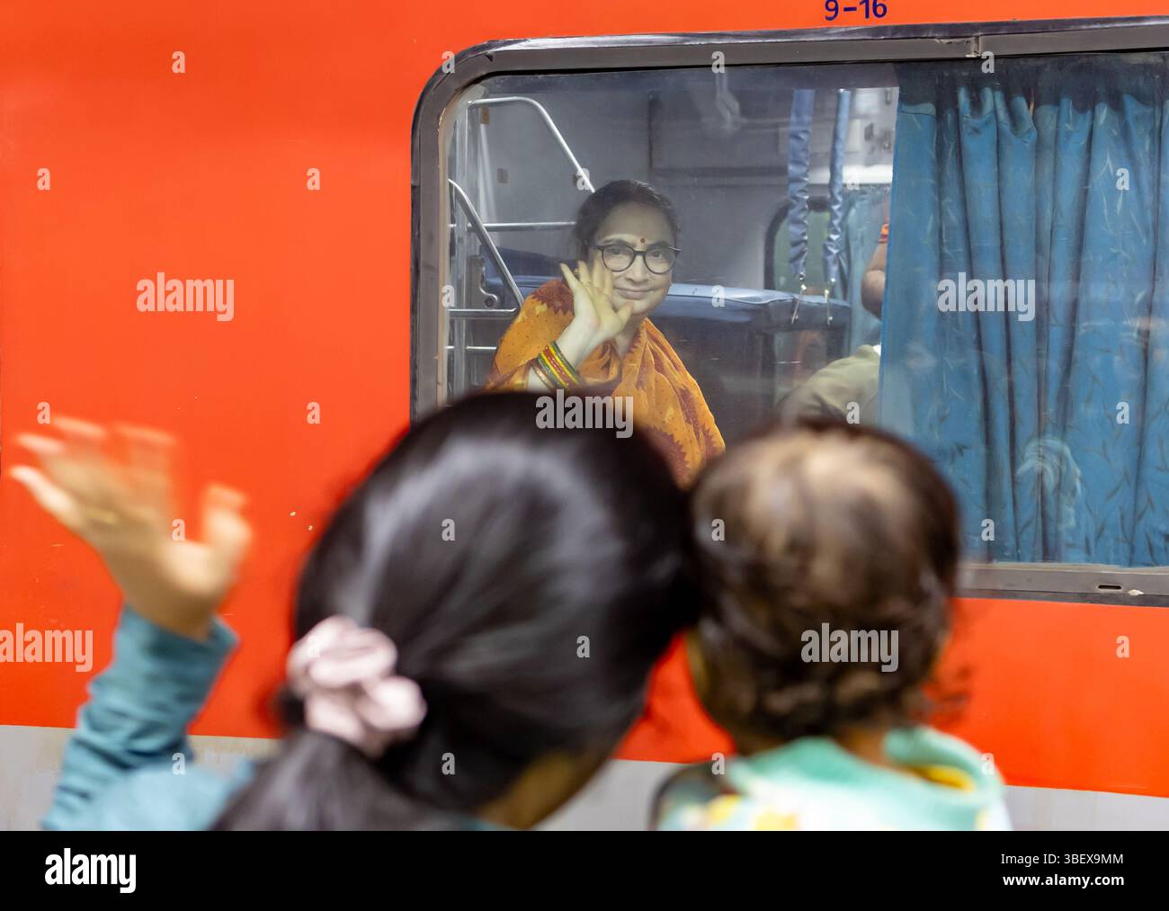 Lady passeggero seduto all'interno del treno che dice addio alla persona amata alla stazione ferroviaria di sera Foto Stock