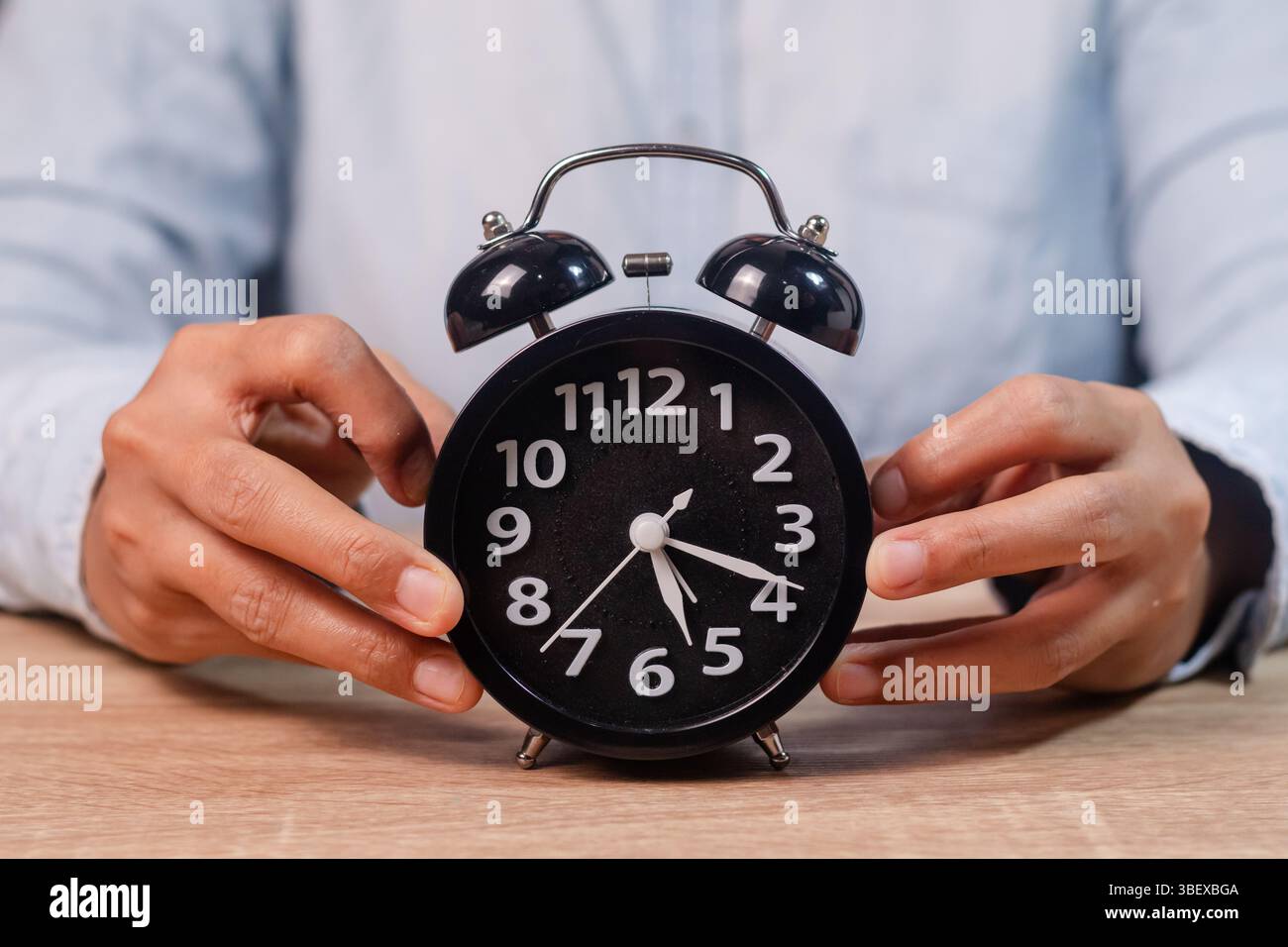 Una donna che tiene una sveglia nera sul tavolo di legno Foto Stock