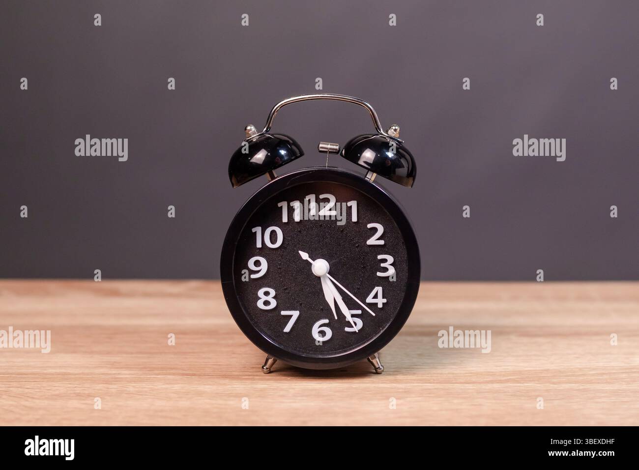 Una sveglia nera su un tavolo di legno Foto Stock