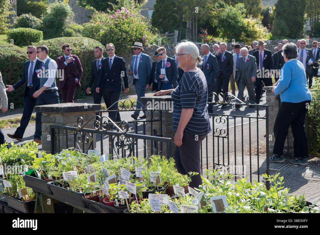 Giornata annuale del Club Walk Day della Long Sutton Friendly Society. Membri, è una società solo maschile che cammina in processione intorno al villaggio fermandosi in varie grandi case per rinfreschi. Due donne che guardano la processione passano accanto. Long Sutton, Somerset, Inghilterra 2019 UK 2010s HOMER SYKES Foto Stock