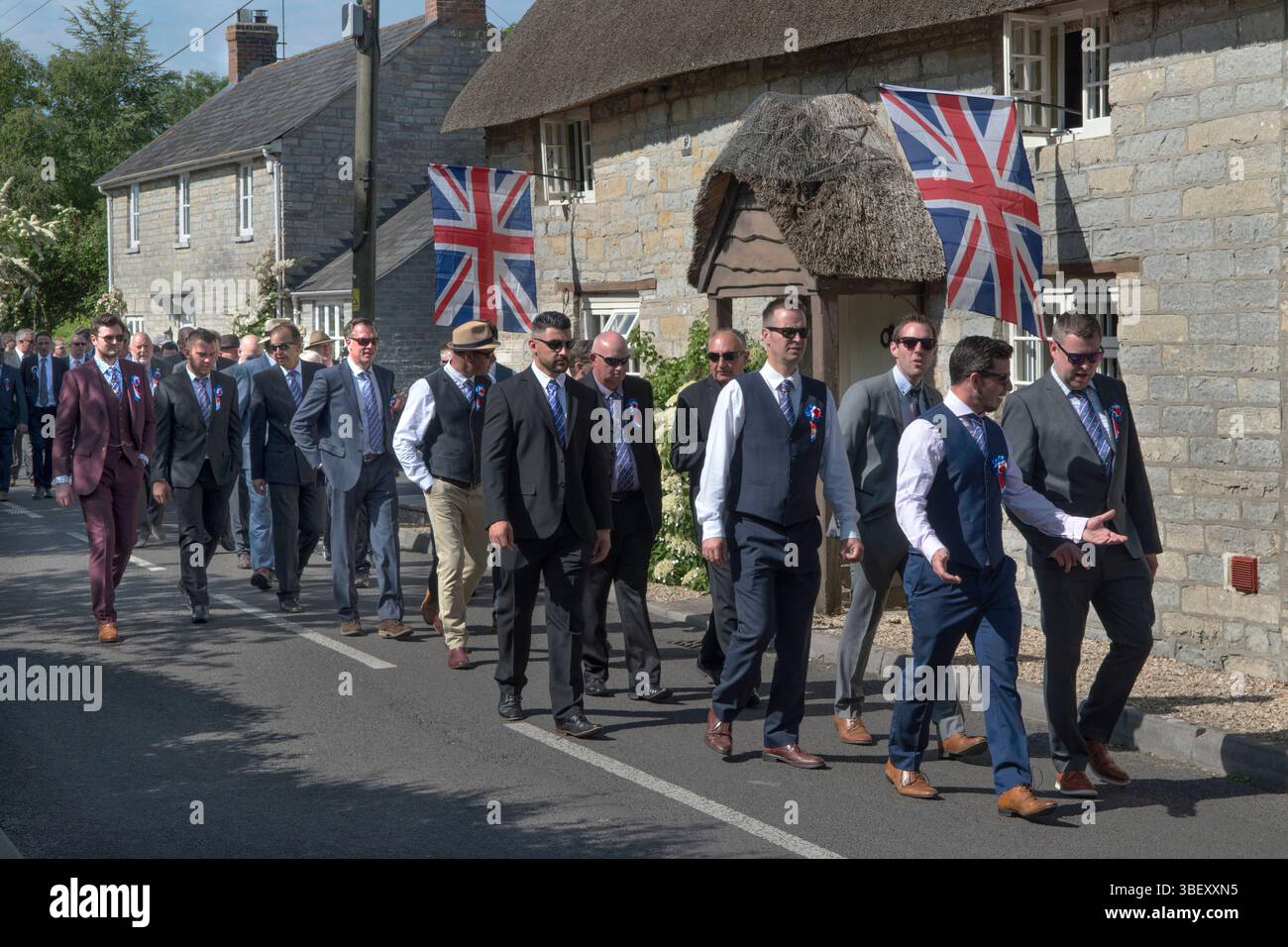 Giornata annuale del Club Walk Day della Long Sutton Friendly Society. Membri, è una società solo maschile che cammina in processione intorno al villaggio fermandosi in varie grandi case per rinfreschi. Cottage del villaggio con bandiere Union Jack. Long Sutton, Somerset, Inghilterra 2019 UK 2010s HOMER SYKES Foto Stock
