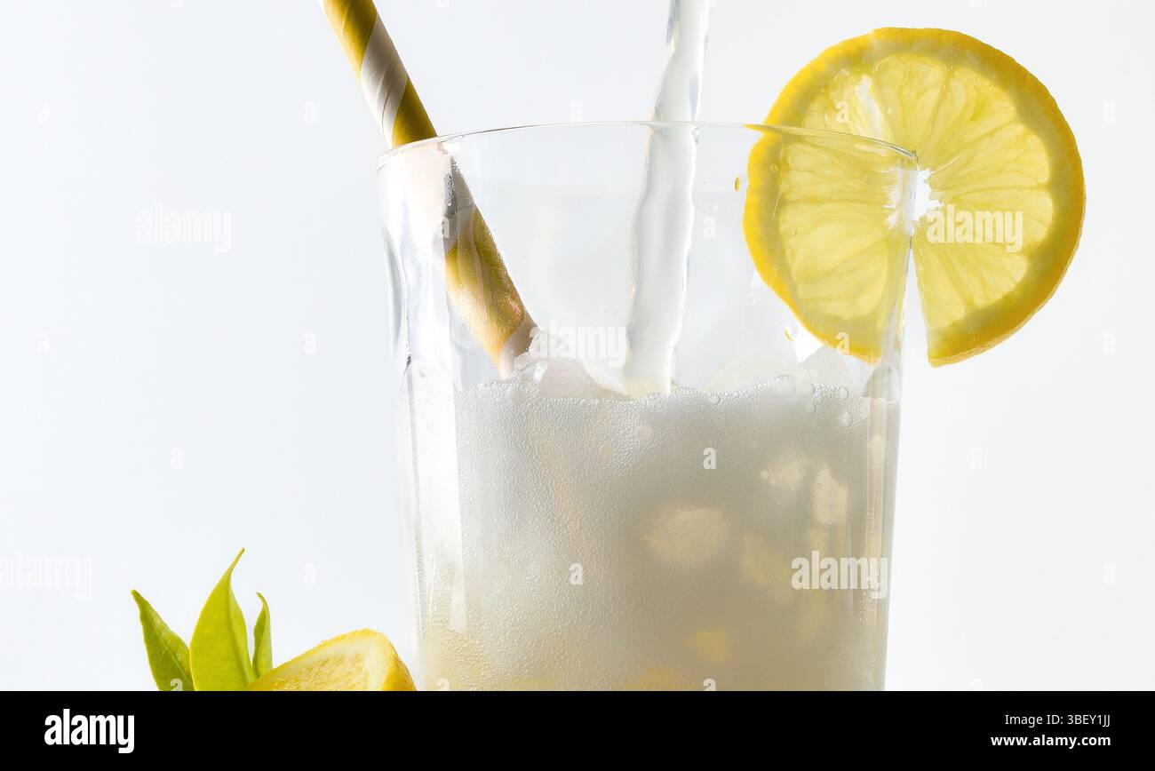 Dettaglio di vetro riempito di limone soda decorato con paglia e fetta di limone, isolato su sfondo bianco. Vista frontale. Foto Stock