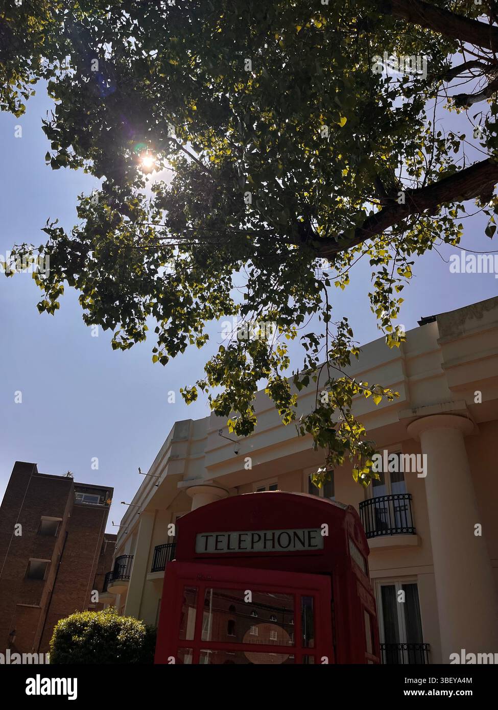 Un'iconica cabina telefonica rossa di London City presso il St Katherine's Docks di Londra, Inghilterra, Regno Unito, Europa, accanto a un edificio estetico in primavera. - Immagine stock catturata con smartphone