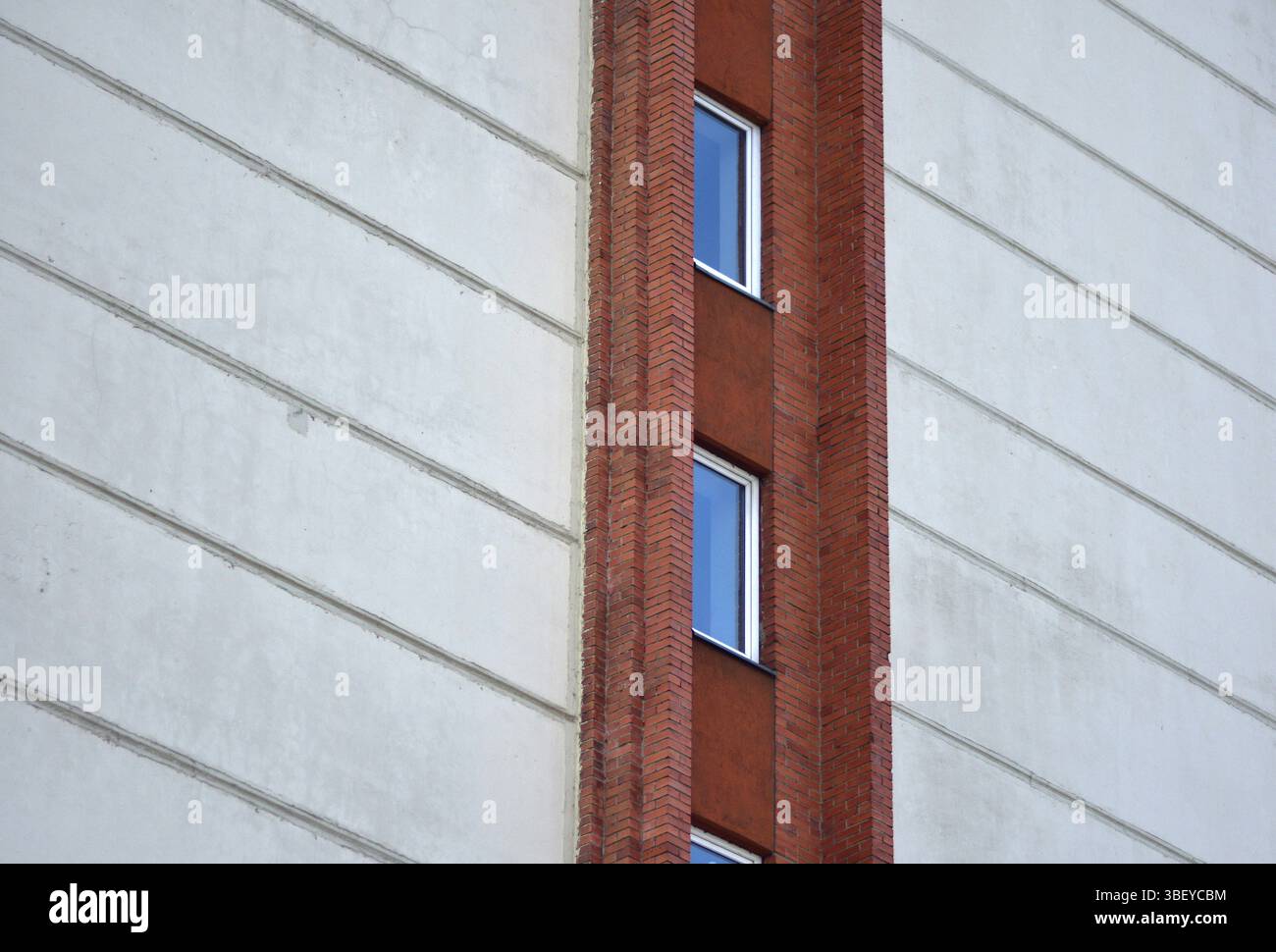 Una vista ravvicinata dell'architettura dell'edificio caratterizzata da strette finestre verticali incorniciate da mattoni rossi e delimitate da blocchi orizzontali bianchi, creando una Foto Stock
