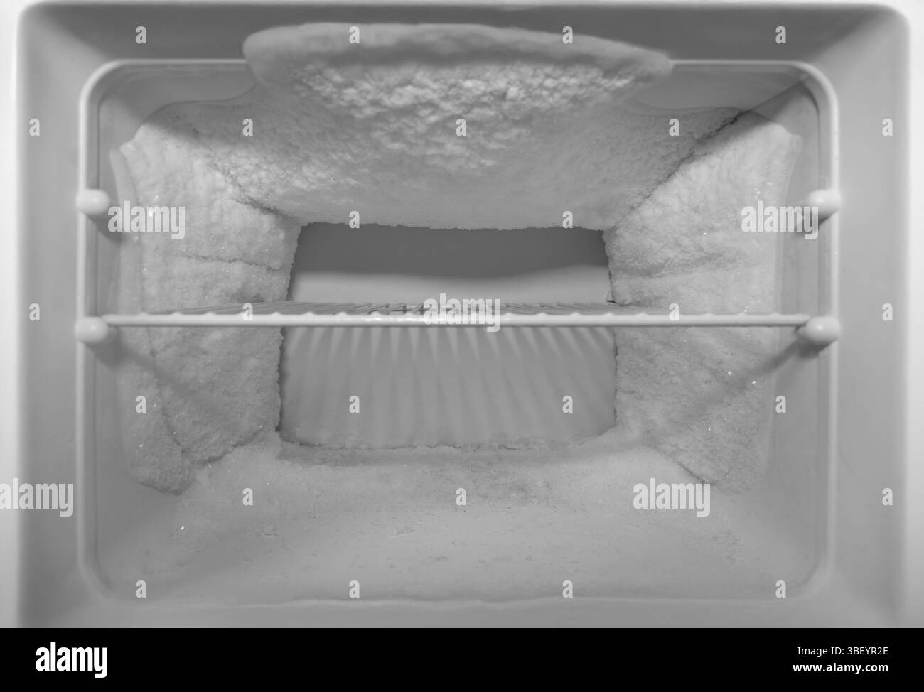 svuotare il congelatore di un frigorifero con ripiano e molto ghiaccio sulle pareti. sbrinamento necessario Foto Stock