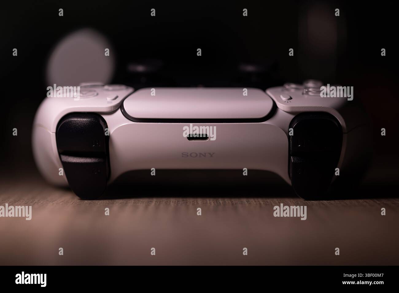 Brecht, Belgio - 18 aprile 2025: Un ritratto scuro di un controller wireless sony playstation 5 originale bianco appoggiato su un tavolo di legno. Pronti a giocare a Foto Stock