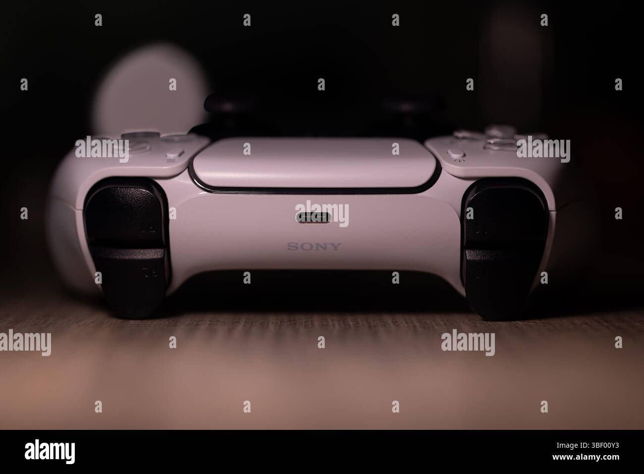 Brecht, Belgio - 18 aprile 2025: Un ritratto scuro di un controller wireless sony playstation 5 originale bianco appoggiato su un tavolo di legno. Pronti a giocare a Foto Stock