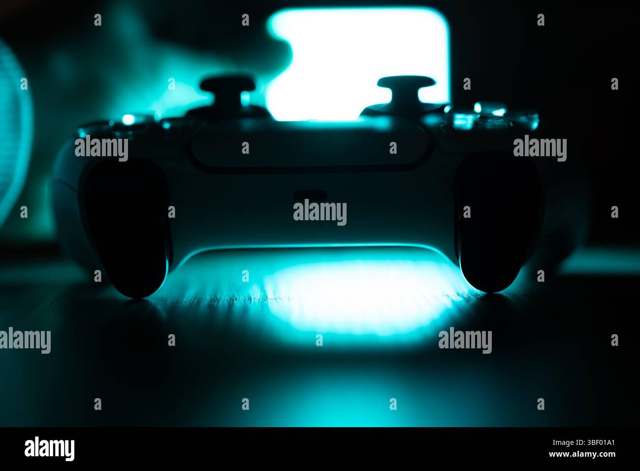 Brecht, Belgio - 18 aprile 2025: Ritratto con la silhouette blu di un controller wireless sony playstation 5 originale bianco appoggiato su un tavolo di legno. Pronti Foto Stock