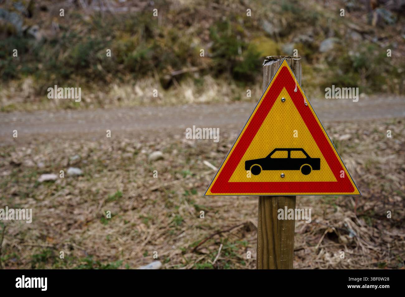 Segnale di avvertimento giallo del veicolo accanto a una strada forestale nella natura selvaggia. Foto Stock