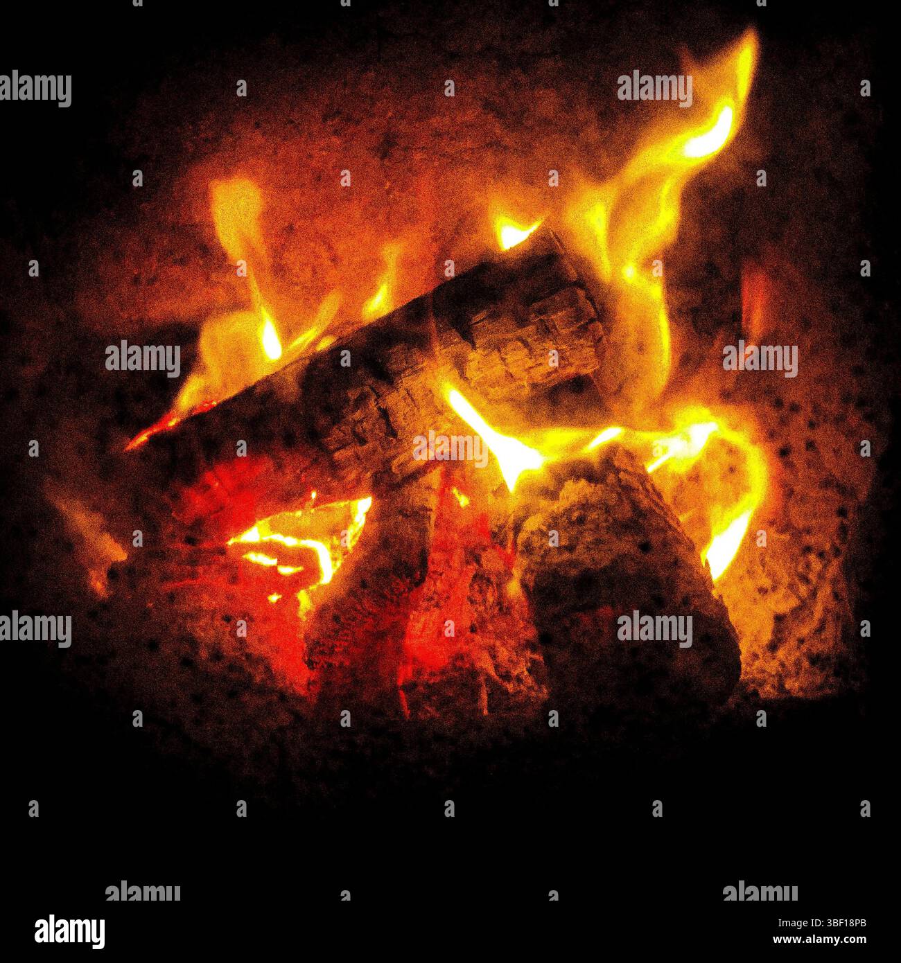 Una calda luce soffusa dal fuoco all'aperto che brucia vecchi tronchi. Foto Stock