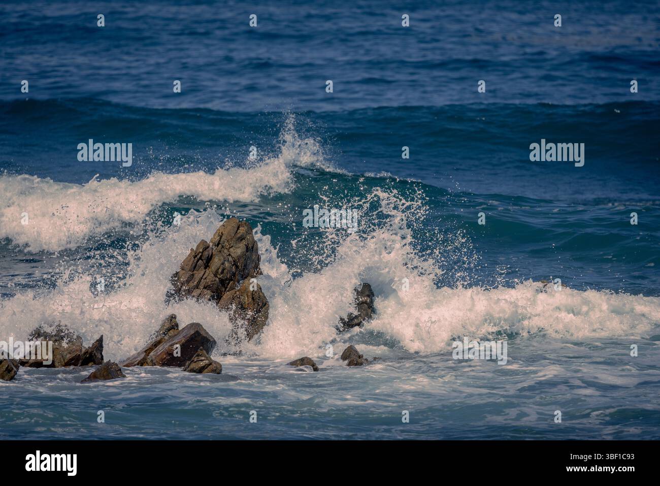 Le potenti onde si scontrano contro rocce aspre lungo la costa sudafricana, catturate con colori e dettagli vivaci. Foto Stock