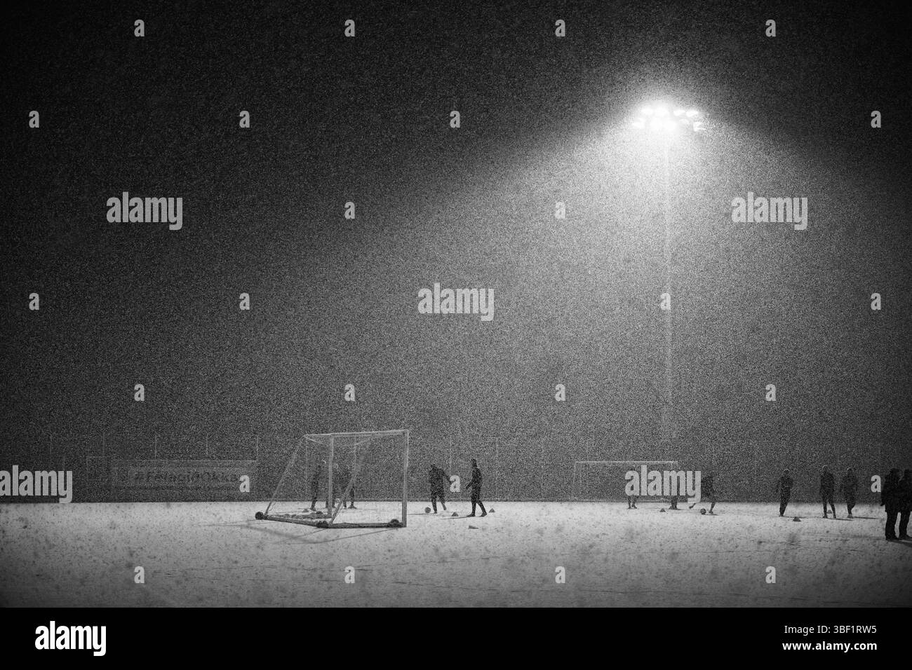 I giocatori di calcio si allenano sotto forti nevicate di notte Foto Stock