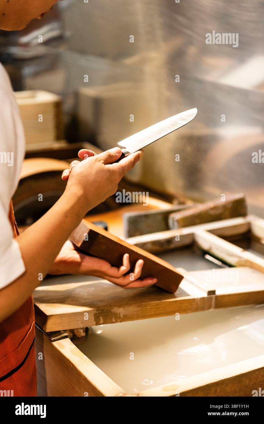 Il lavoratore affila il coltello al mercato Nishiki, Kyoto, Giappone. Foto Stock