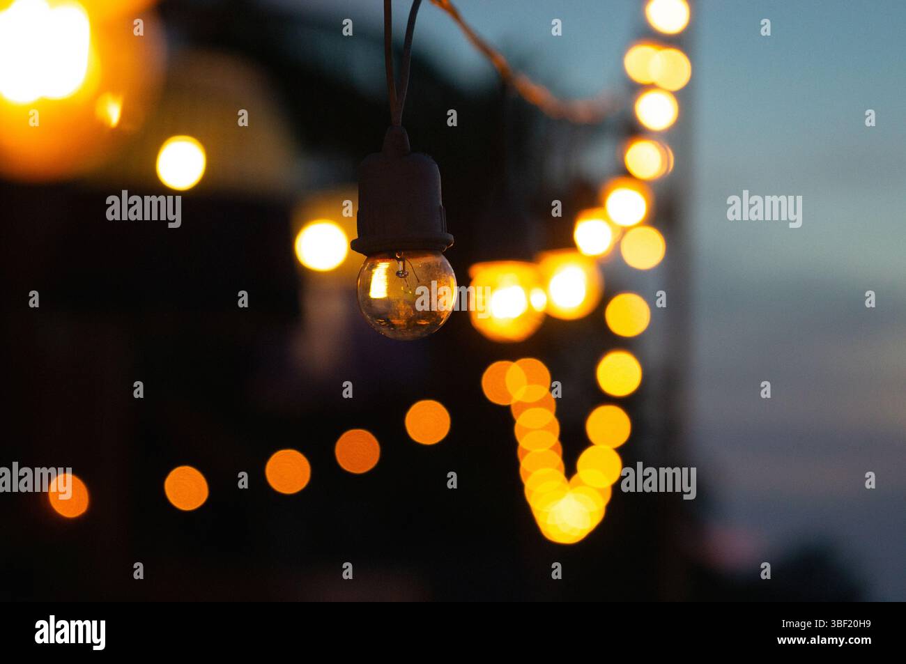 Luci a corda accese in un bokeh da sogno al crepuscolo Foto Stock
