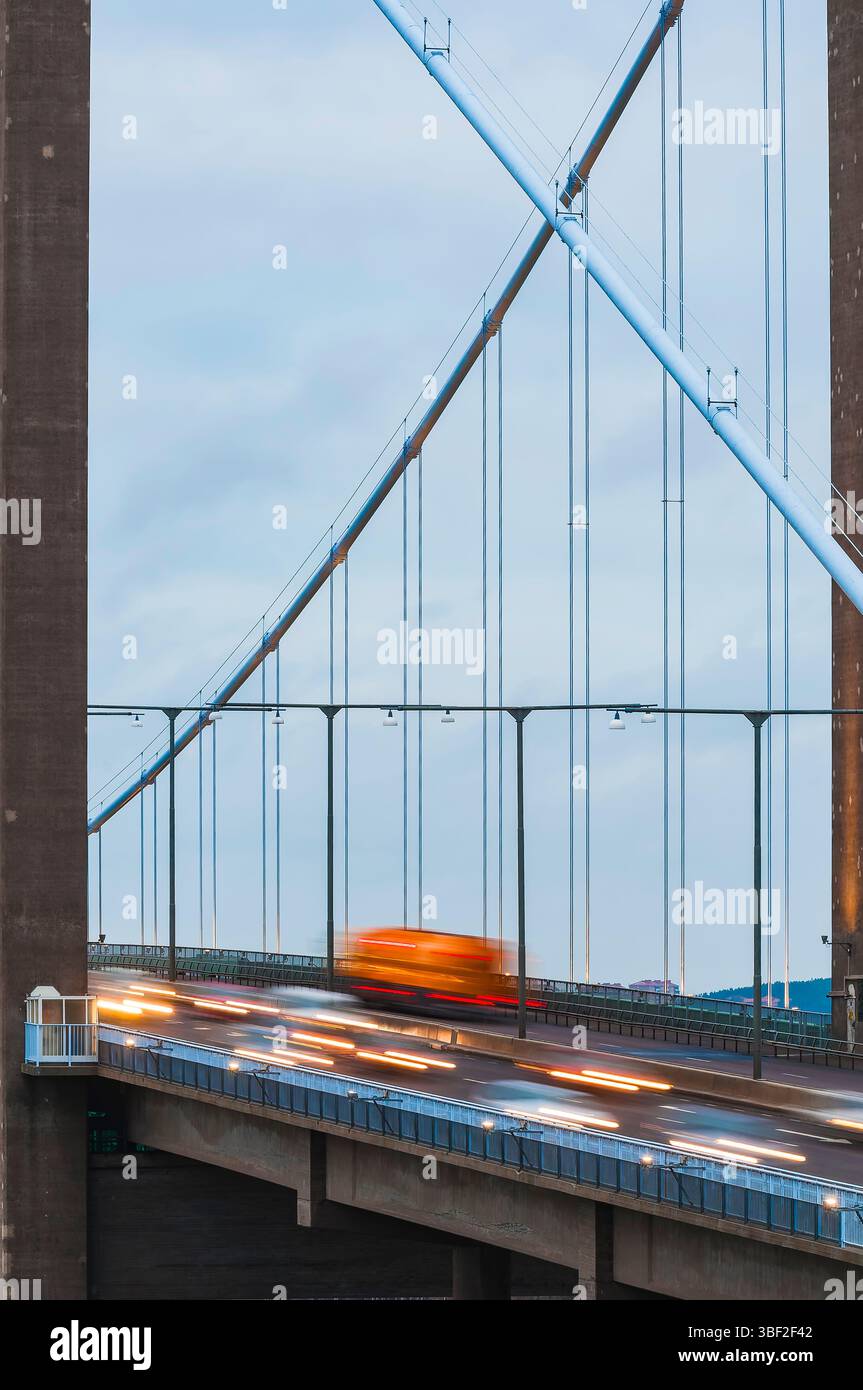 I veicoli si muovono rapidamente attraverso Älvsborgsbron, catturando l'energia vibrante dei trasporti di Goteborg. Il cielo nuvoloso aggiunge un'atmosfera unica al tuo Foto Stock
