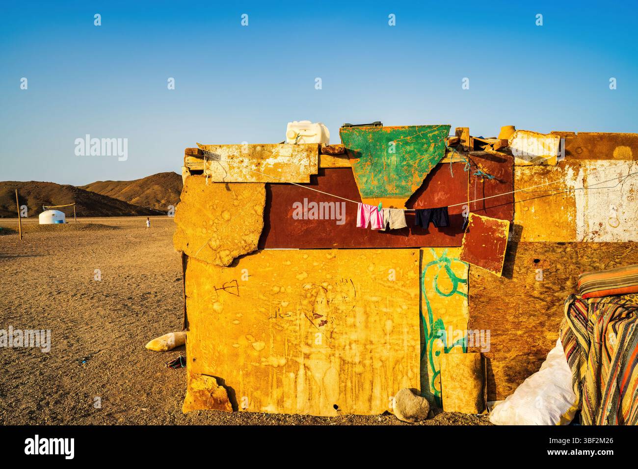 Pareti colorate di cemento intemprato in vibranti gialli, rossi e verdi con lavanderia appesa in un villaggio egiziano nel deserto Foto Stock