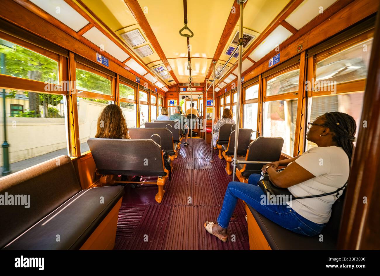 Interno di uno storico tram 18E di Lisbona con passeggeri che si godono un giro panoramico attraverso la città. Fascino vintage. Foto Stock