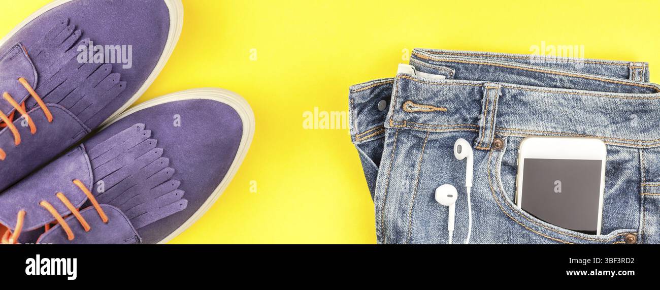 Piatto di laici scarpe scamosciate, jeans blu, grigio hat, cactus e lo smartphone cuffie sul bold carta gialla sfondo con copia spazio. Vista aerea del woma Foto Stock