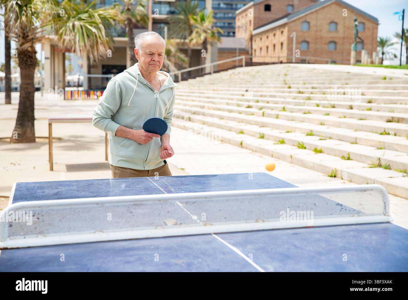 Gioco urbano di ping pong all'aperto con senior Foto Stock
