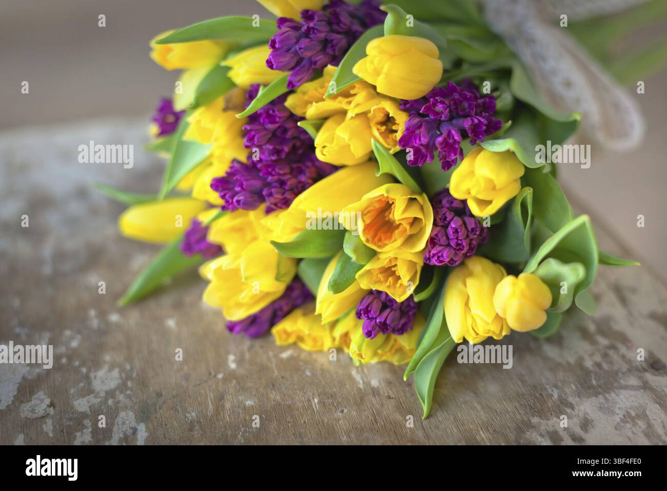 Tulipani gialli e viola giacinti bouquet di fiori su un tavolo di legno. In interni luce naturale shot con piccole profondità di campo Foto Stock