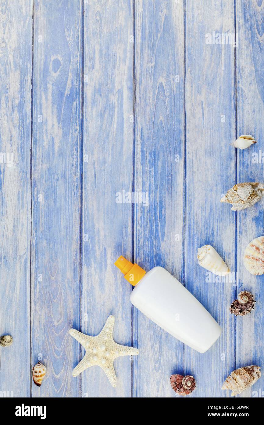 Piatti creativi concetto laici estate vacanze di viaggio. Vista superiore della bottiglia per la protezione solare mockup conchiglie e stelle marine sul pastello blu doghe in legno sfondo Foto Stock