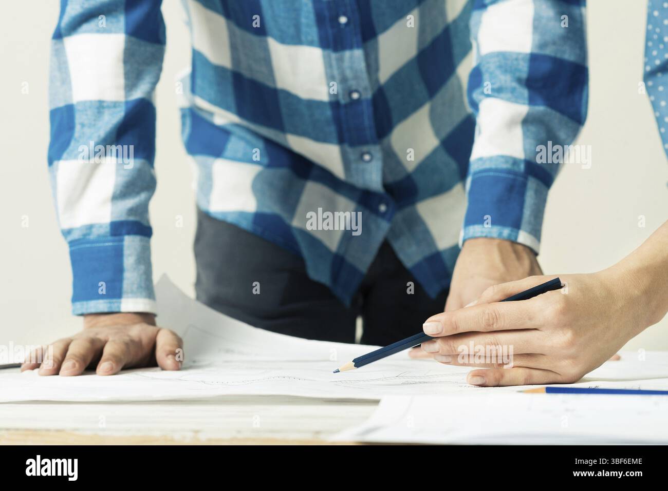Discussione del progetto nello studio di architettura. Architetto che analizza il progetto cartaceo. Primo piano uomo che punta con una matita sul disegno di costruzione. Foto Stock