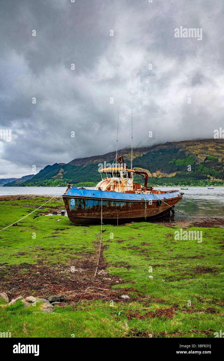 Barca trasportata sulle rive del Loch Duich sotto un cielo cupo, suggestiva scena delle Highlands piena di umore e drammi. Foto Stock