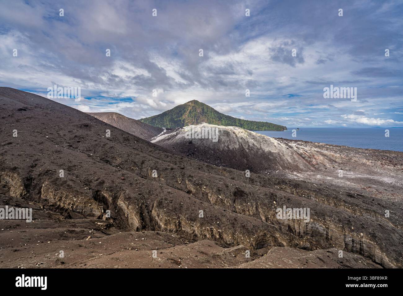 Vista del paesaggio minerale di Anak Krakatau o del vulcano Krakatoa nello stretto della sonda con sullo sfondo l'isola di Sertung o Verlaten, Lampung, Sumatra, Indonesia Foto Stock