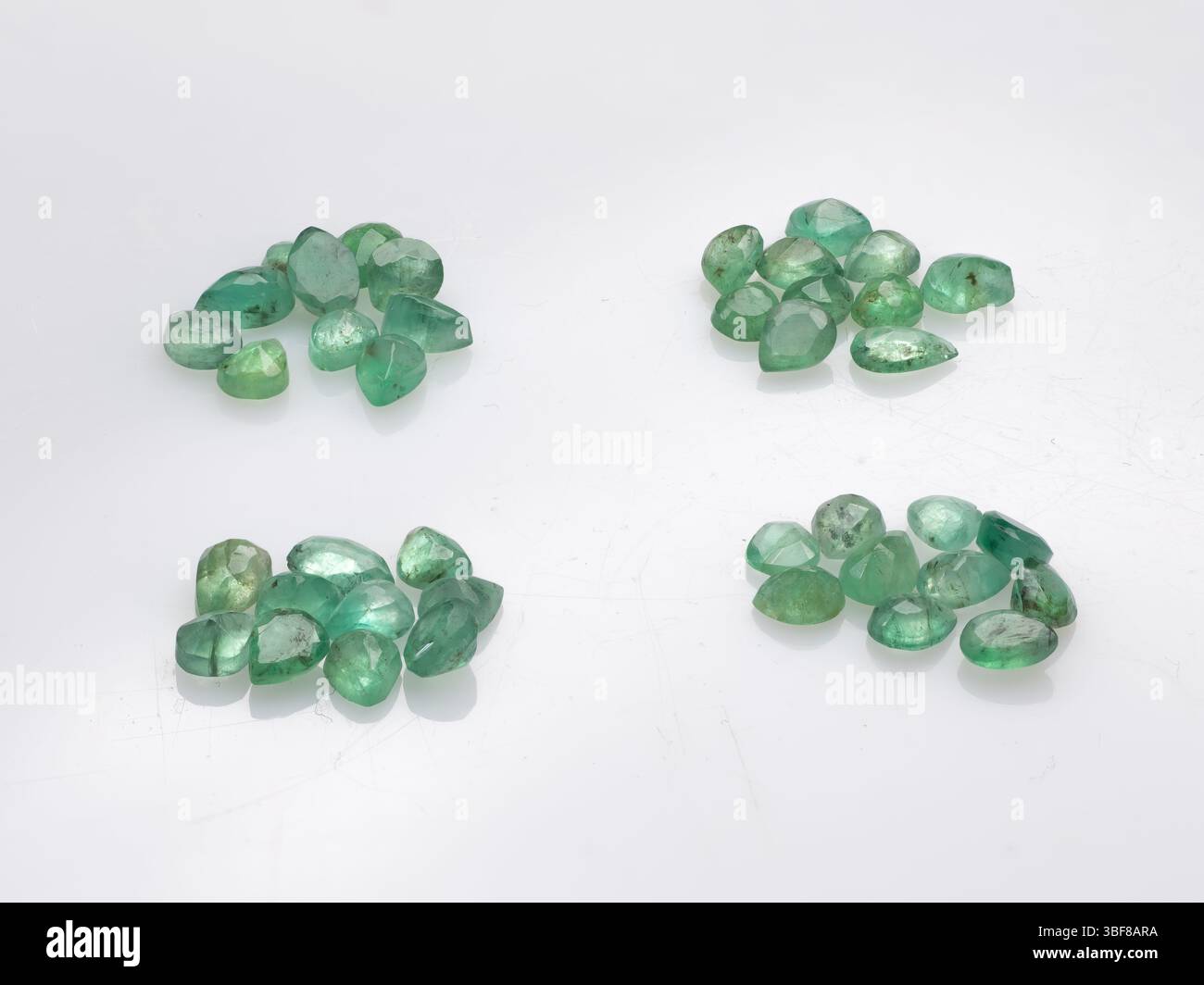 Una collezione di pietre preziose di smeraldo naturali intatte che presentano vivaci sfumature verdi e cluster di cristallo grezzo perfetti per il design di gioielli e collezionisti di minerali Foto Stock