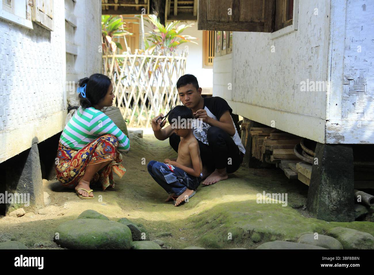 I genitori stanno rifilando i capelli dei loro figli con semplici forbici e pettini in tutta la casa. Foto Stock