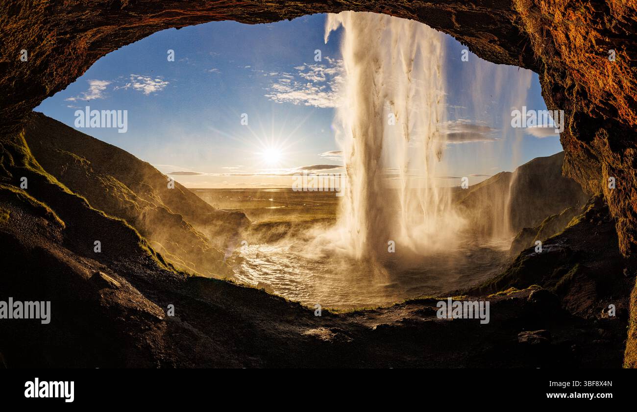 La vista della cascata Seljalandsfoss dall'interno della cascata con un incredibile tramonto in una tranquilla area paesaggistica del cerchio d'Oro in Islanda Foto Stock