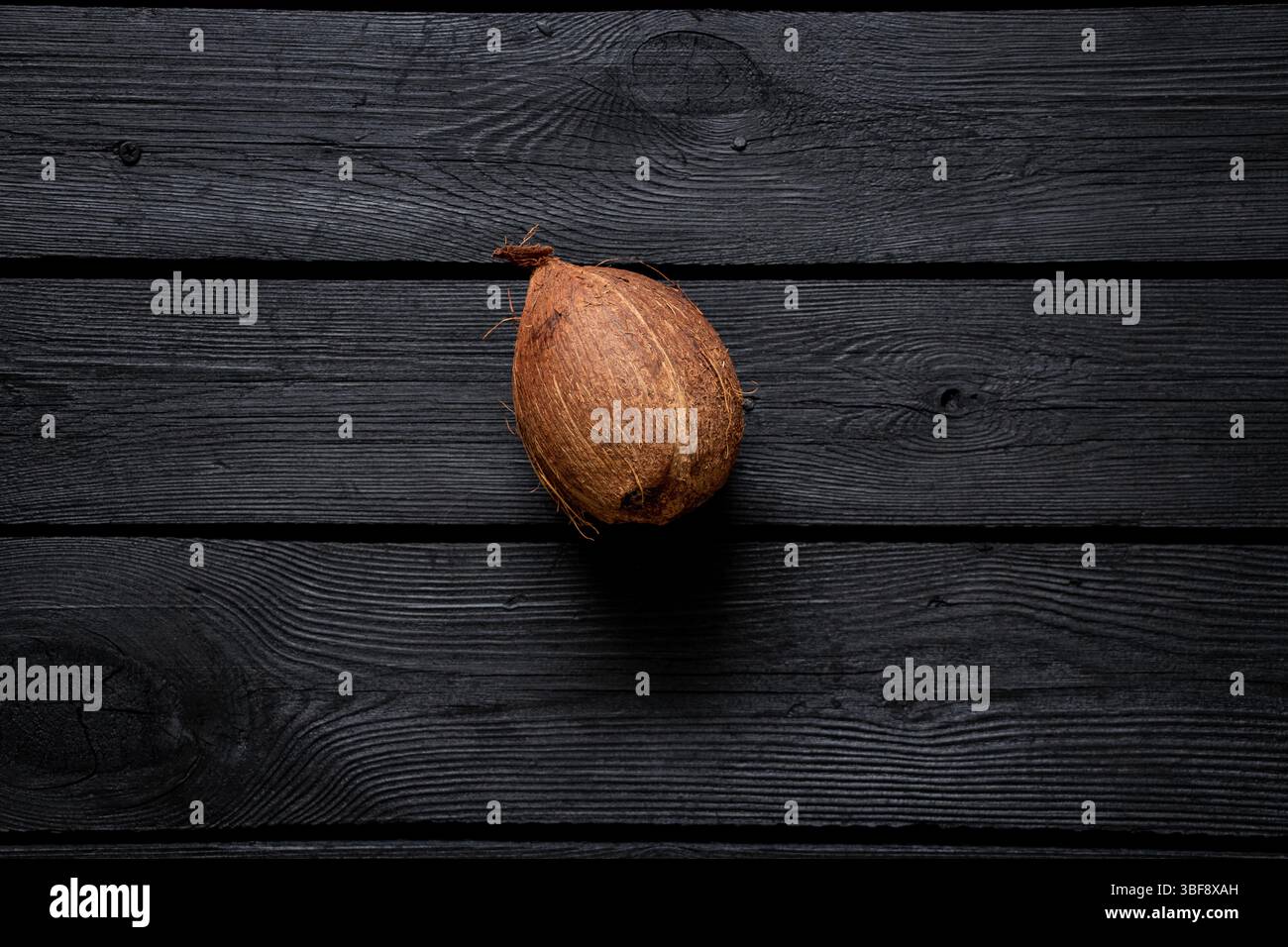 Noce di cocco su una superficie in legno nero, primo piano, frutta tropicale Foto Stock