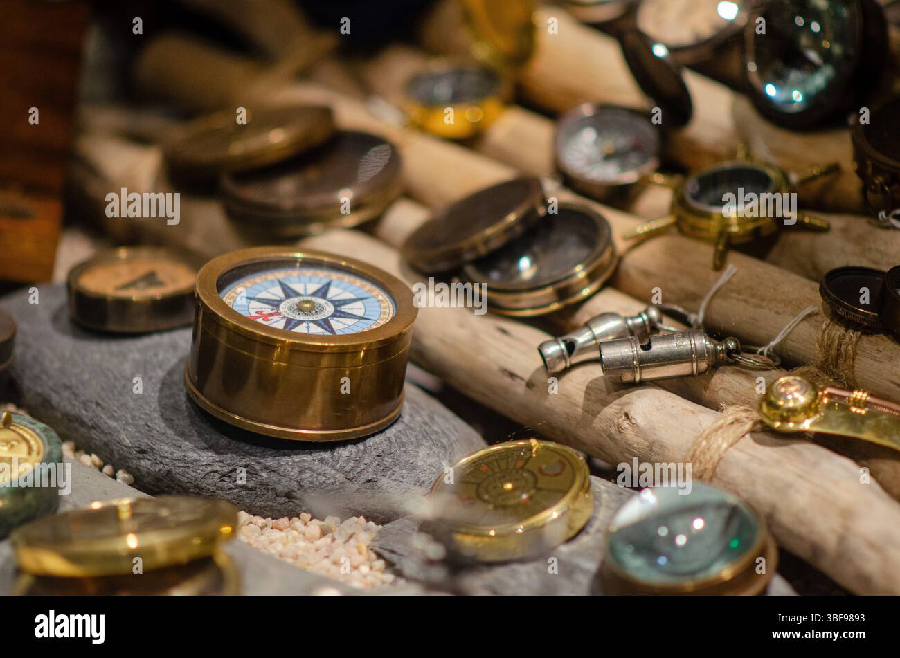 Bussole in ottone antico assortite esposte su una superficie in legno testurizzato, evocano un'avventura nautica e classici temi di esplorazione marittima. Foto Stock