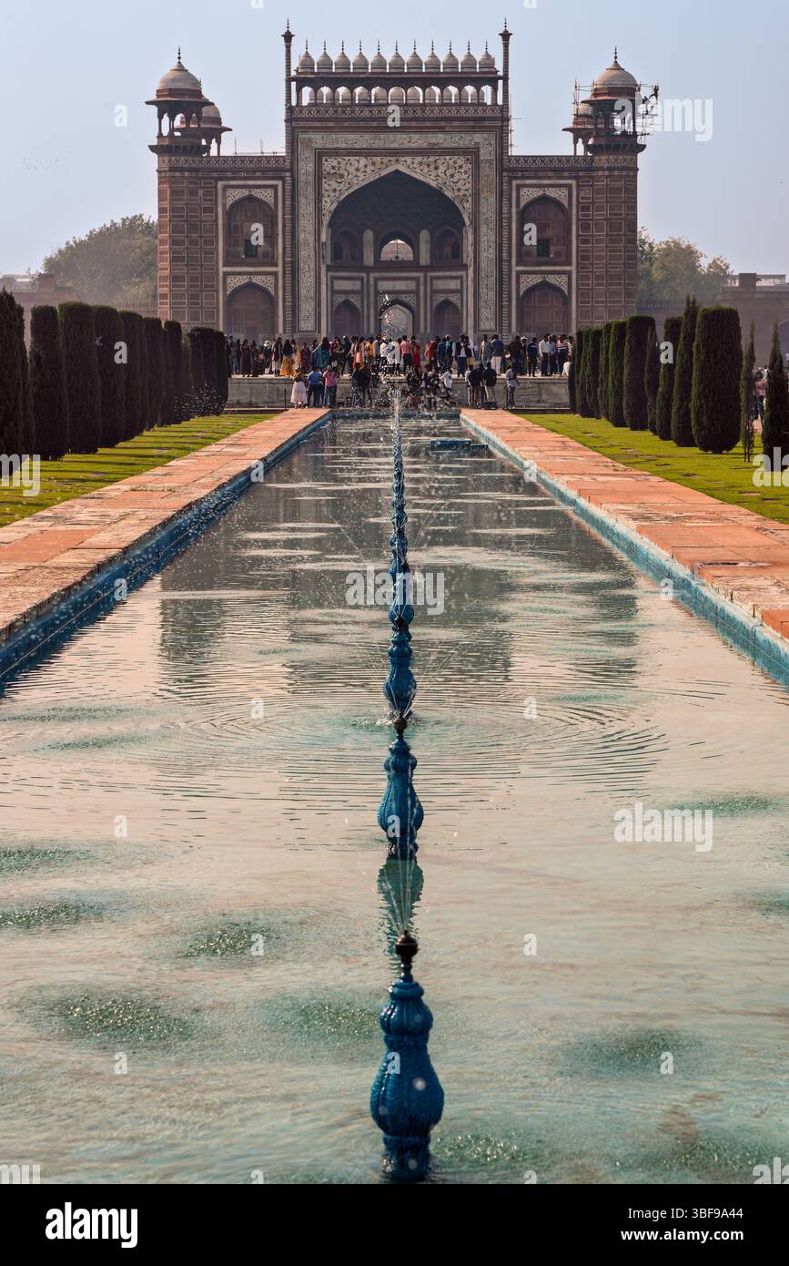 Cancello d'ingresso del Taj Mahal, Agra, India. Il cancello d'ingresso del Taj Mahal, noto come la grande porta o Darwaza-i-Rauza, è la grande porta principale per l'iconico mausoleo di Agra, in India. Costruito in arenaria rossa con intricato intarsio di marmo bianco, fu completato intorno al 1648. Il cancello presenta iscrizioni coraniche e motivi floreali che riflettono l'eleganza architettonica moghul. Svolge un ruolo sia cerimoniale che simbolico, preparando i visitatori allo splendore del Taj Mahal Beyond. Foto Stock