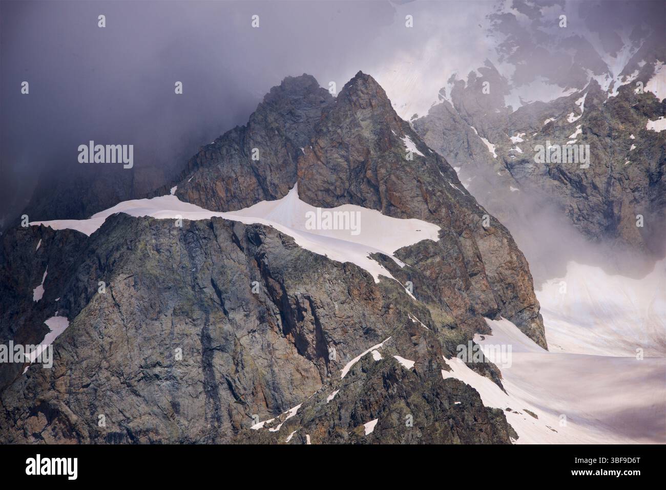 Neve sulle pendici superiori delle montagne che circondano la valle Vallouise appena a nord di Ailefroide, Vallouise-Pelvoux, Hautes-Alpes, Francia. Fotografato a giugno dal Pré de Madame Carle. Foto Stock