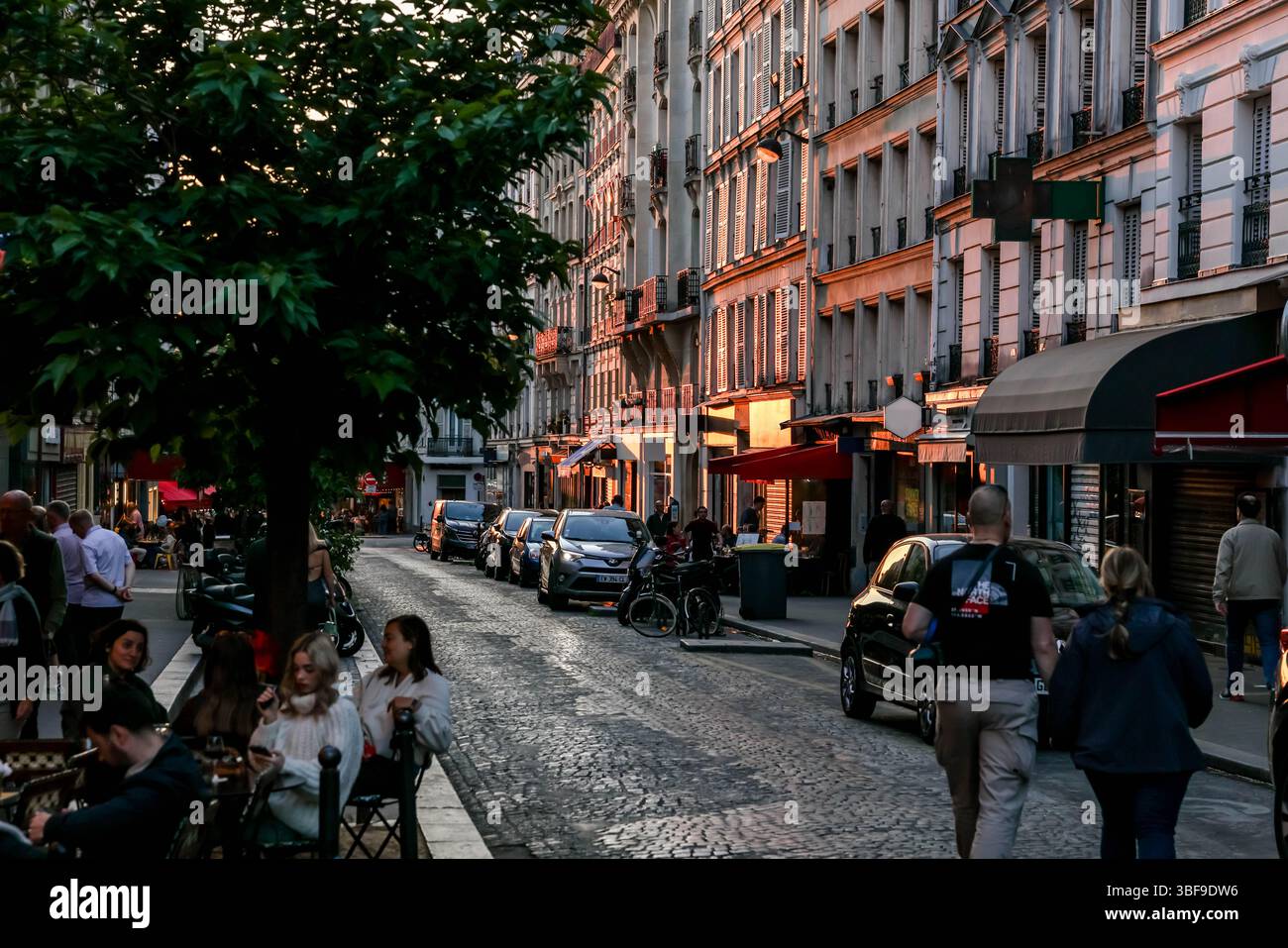 La vivace Rue des Abbesses di Parigi si anima di sera, con gente che passeggiava, cenava in caffetterie all'aperto e curiosava nei negozi come "Fromagerie" Foto Stock