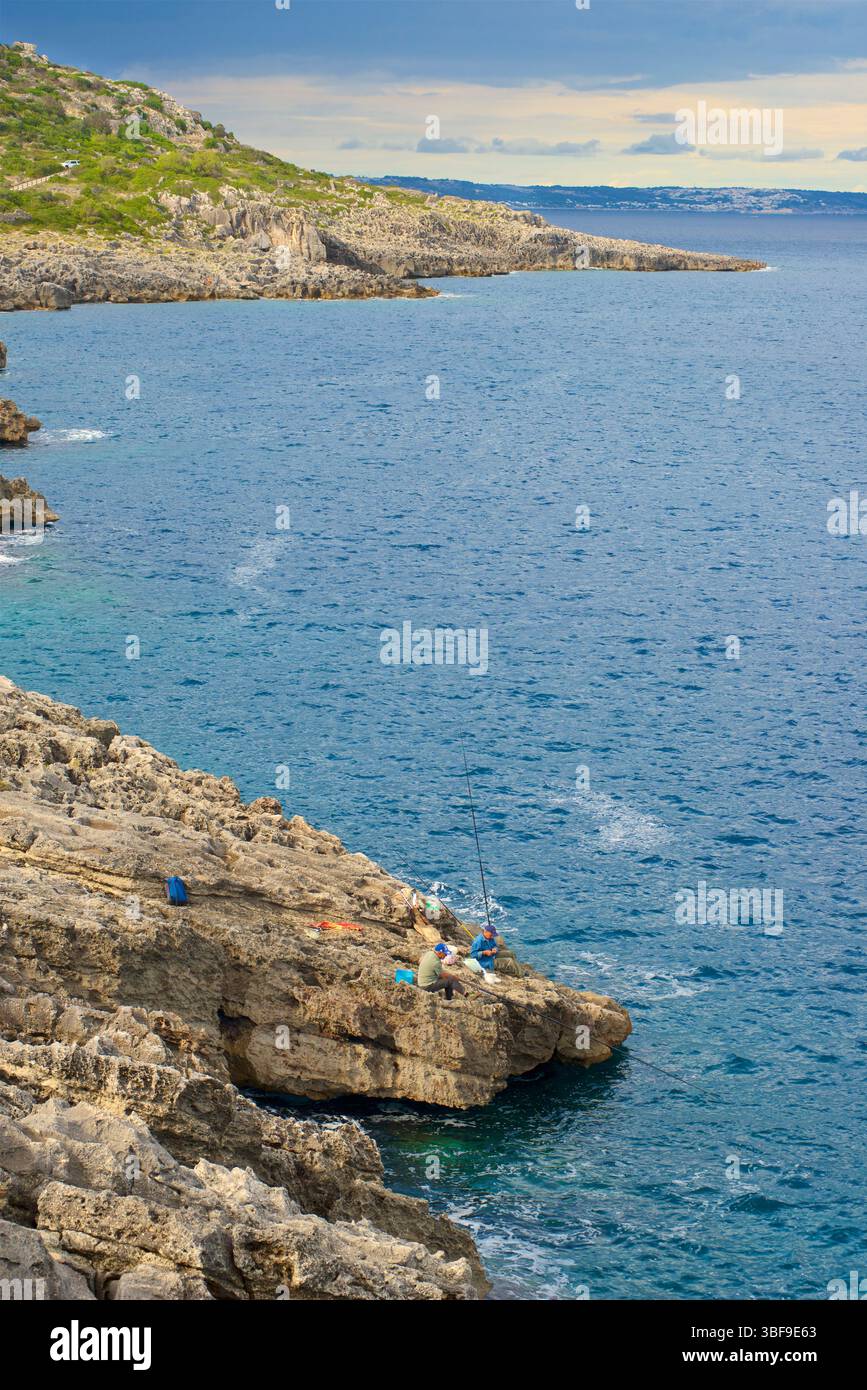 Pescatori, pesca da scogli con canne da pesca alla spiaggia di Funnov˜jere, nel comune di Corsano, nella parte sud-occidentale del Salento, in provincia di Lecce, Puglia, Italia. Questo angolo nascosto si affaccia sul mare Adriatico, caratterizzato da scogliere e rocce a picco sul mare, Foto Stock