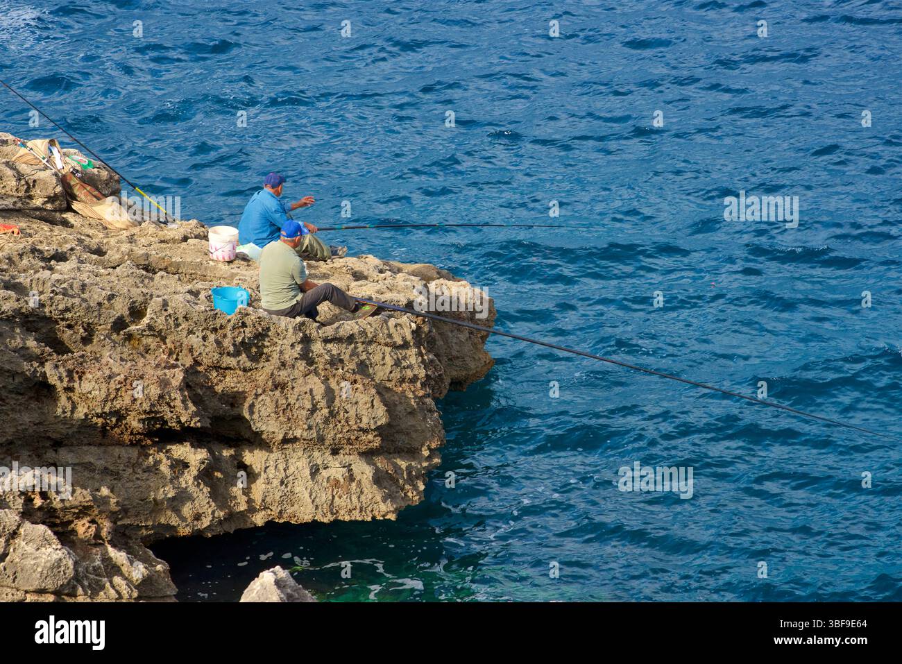 Pescatori, pesca da scogli con canne da pesca alla spiaggia di Funnov˜jere, nel comune di Corsano, nella parte sud-occidentale del Salento, in provincia di Lecce, Puglia, Italia. Questo angolo nascosto si affaccia sul mare Adriatico, caratterizzato da scogliere e rocce a picco sul mare, Foto Stock