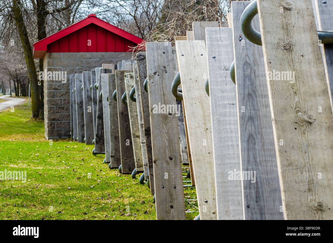 Tavoli da picnic impilati contro un capannone di mattoni con un tetto in acciaio res, accanto all'erba verde sotto un cielo blu in primavera Foto Stock