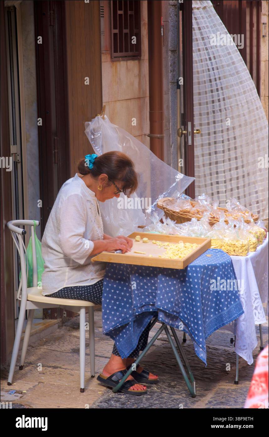 La pasta alle orecchiette viene prodotta nelle strade secondarie di Bari, Puglia, Italia. La parola deriva dall'italiano orecchia, lett.?'Ear', e -etta) una pasta tipica della Puglia. Il loro nome deriva dalla loro forma, che assomiglia a un piccolo orecchio. Nel 2019 il New York Times pubblicò un articolo intitolato ÒA Crime of PastaÓ. Si è scoperto che un ristorante a Bari usava orecchiette non rintracciabili. Bari è conosciuta per le sue strade fiancheggiate da ÒnonnasÓ della nonna che vende pasta fatta in casa. Secondo la legge italiana è legale vendere piccoli sacchi a privati, anche se senza licenza di vendita le spedizioni ai ristoranti sono illegali Foto Stock