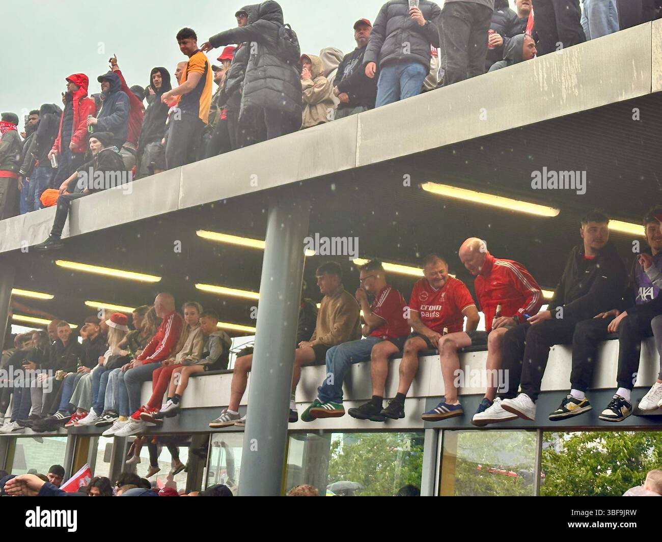 I tifosi del Liverpool riempiono due tetti della stazione degli autobus di Strand Street durante la parata della vittoria della Premier League, 25 maggio 2025 - Immagine stock catturata con smartphone