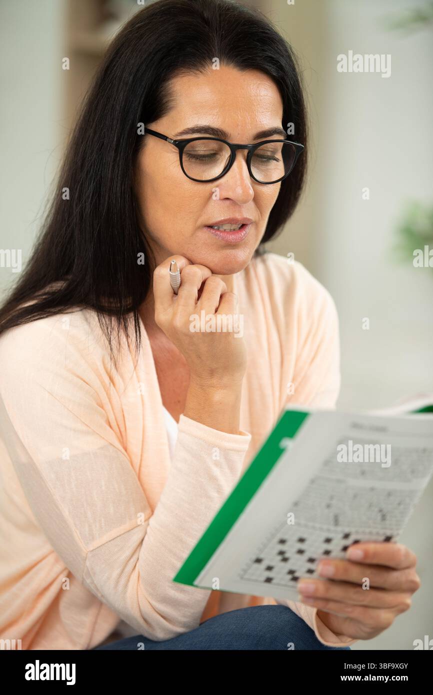 premuroso attraente donna che risponde cruciverba puzzle Foto Stock