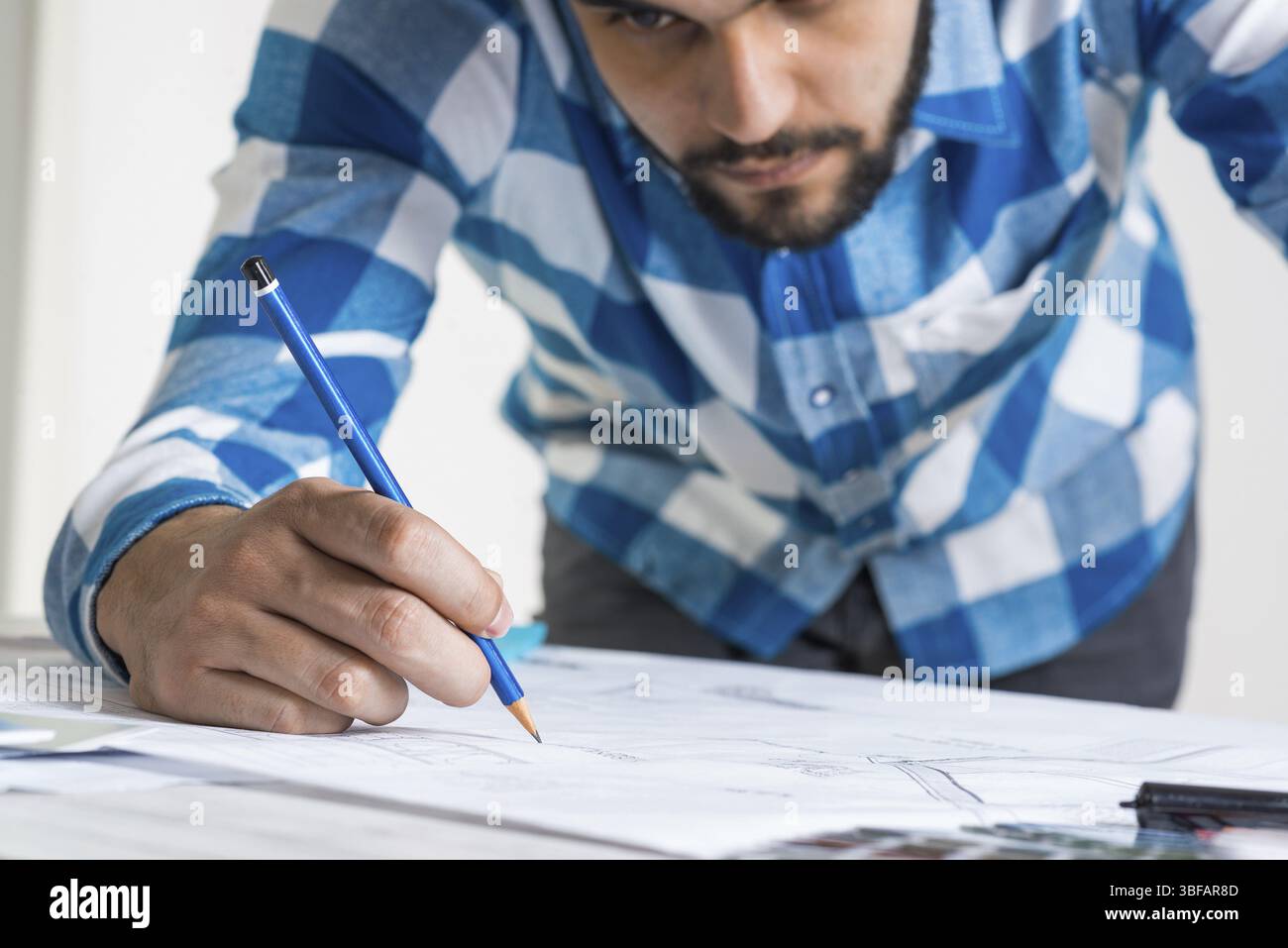 Uomo che disegna con una matita il progetto di costruzione. Progettare il luogo di lavoro con disegni tecnici. Concept di studio di architettura con progetto di design. Profes Foto Stock