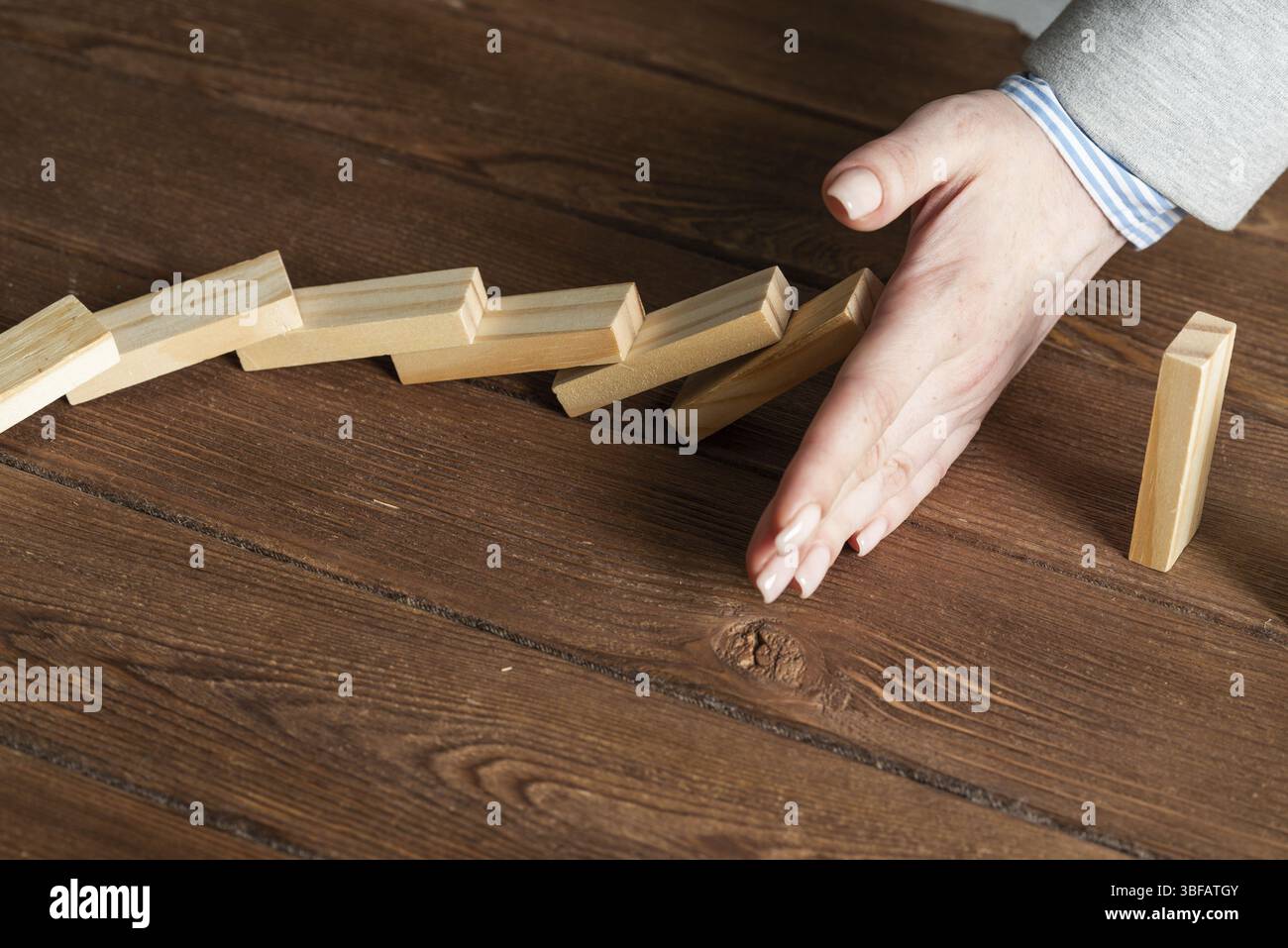 Donna d'affari blocco a mano effetto domino. Gestione del rischio aziendale e situazione di stabilizzazione. Presentazione della compagnia di assicurazione vita con blocchi di legno Foto Stock