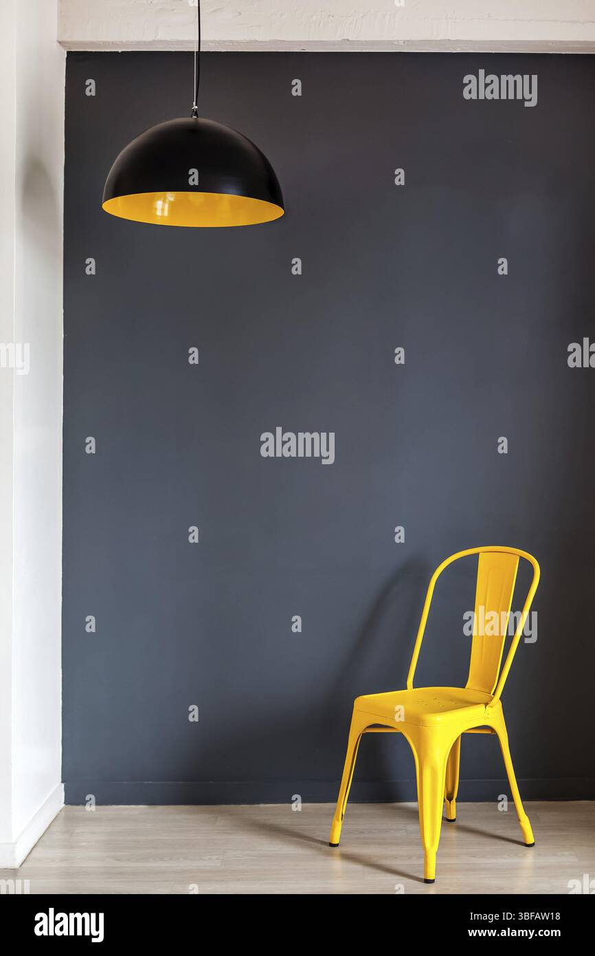 Il muro del soggiorno è mock up con parete grigio scuro e audace sedia e lampada gialla Foto Stock