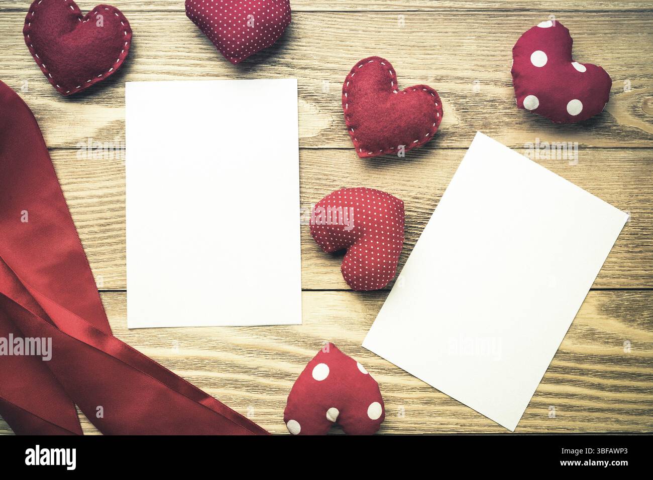 Cuori di amore e di un foglio di carta bianca sul tavolo di legno Foto Stock