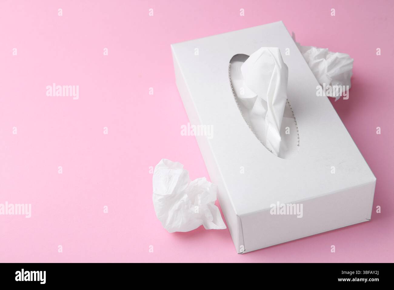 Scatola con fazzoletti di carta e fazzoletti su sfondo rosa, primo piano. Spazio per il testo Foto Stock