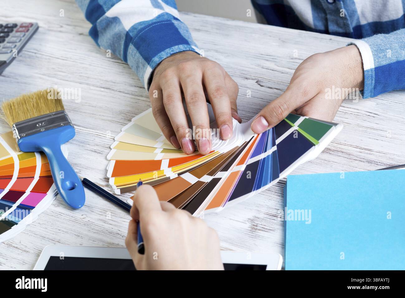 Designer di interni che sceglie i colori dai campioni alla scrivania in legno. Ambiente di lavoro in studio di progettazione. Selezione della tavolozza dei colori per la progettazione. Professionale Foto Stock