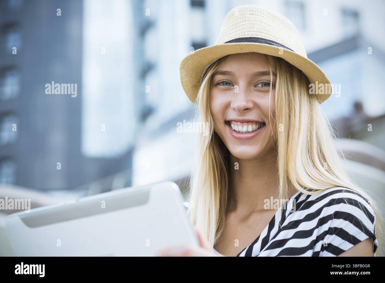 Giovane donna bionda che usa la tavoletta mentre si siede all'aperto sulla scala fasi Foto Stock
