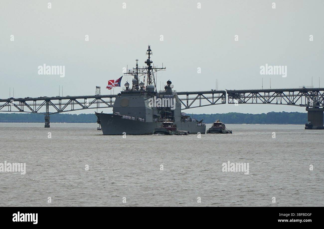 Yorktown, Virginia (31 maggio 2025) l'incrociatore missilistico guidato classe Ticonderoga USS Gettysburg (CG 64) transita sul fiume York con il Coleman Bridge sullo sfondo mentre l'incrociatore si prepara ad ormeggiare al molo delle armi R-3 a bordo della Naval Weapons Station Yorktown. L'incrociatore, portato a Norfolk, Virginia, e il suo equipaggio stavano tornando a Yorktown per scaricare le armi dopo un dispiegamento di quasi 9 mesi nelle aree di responsabilità del comando centrale e europeo degli Stati Uniti. Decine di familiari e persone a carico hanno atteso con ansia l’arrivo dell’incrociatore al molo. (Foto della Marina degli Stati Uniti di Max Lonzanida/R. Foto Stock